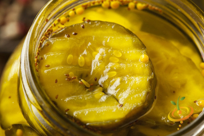 Close-up of sliced pickled cucumber with mustard seeds in jar, representing National Pickling seeds variety