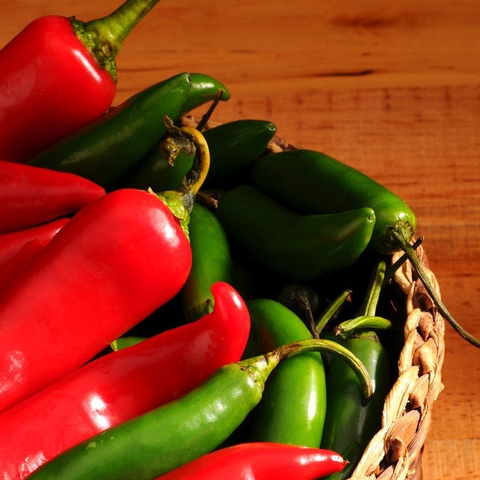 Basket of green and red Serrano Tampiqueño peppers on wooden surface