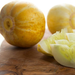 Lemon cucumber whole and sliced on wooden surface showing yellow skin and pale green interior